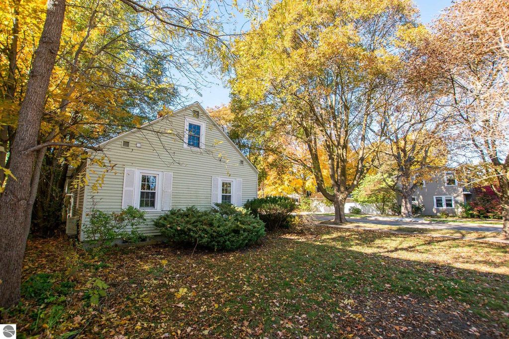 Two-bedroom ranch home on oversized lot with autumn foliage, located at 1101 Jefferson Avenue, Traverse City, MI, showcasing potential for renovation or new construction.
