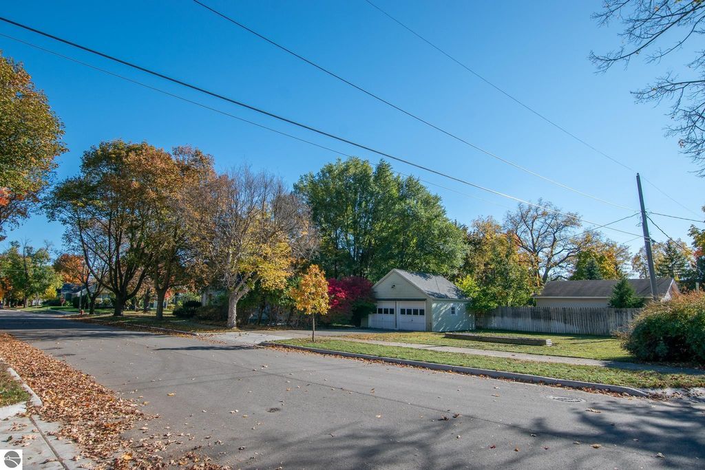 Street view of 1101 Jefferson Avenue in Traverse City, showcasing residential homes, colorful autumn foliage, and a clear blue sky, emphasizing the neighborhood's charm and potential for development.