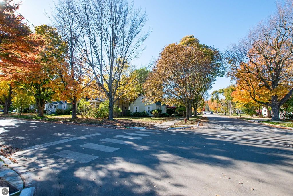 Autumn view of tree-lined street in Traverse City, Michigan, showcasing vibrant fall foliage and residential homes, relevant to real estate listing at 1101 Jefferson Avenue.