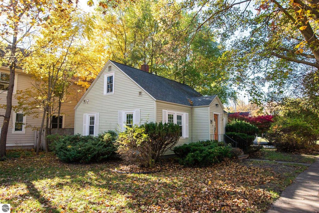 Charming 2-bedroom ranch home at 1101 Jefferson Avenue, surrounded by colorful autumn foliage, showcasing potential for renovation or new construction in Traverse City's Slabtown neighborhood.
