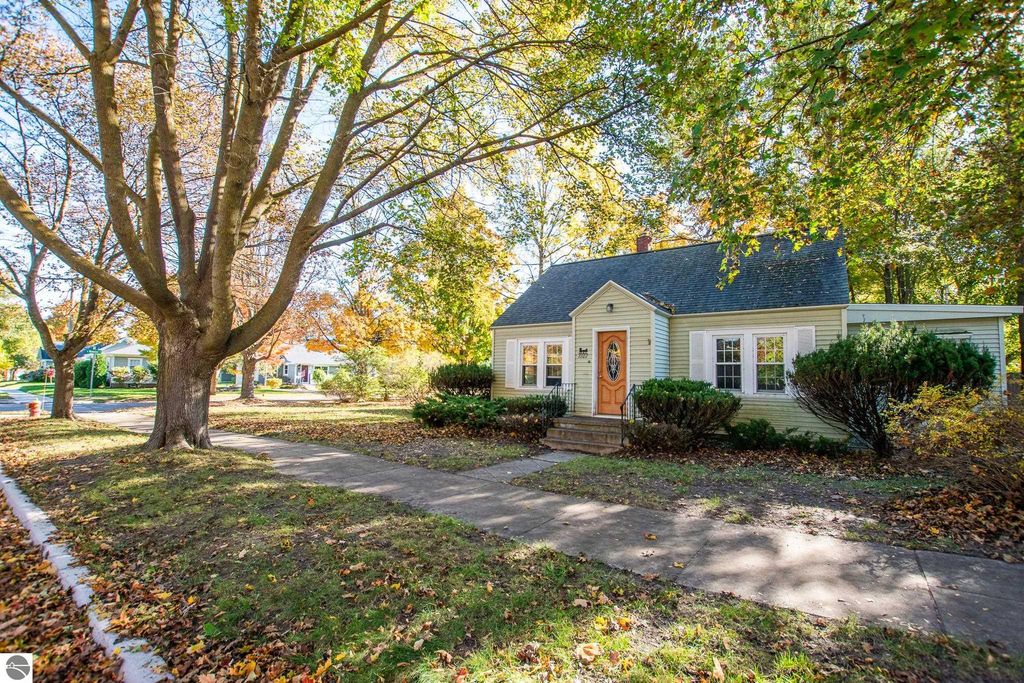 Charming 2-bedroom ranch home at 1101 Jefferson Avenue in Traverse City, surrounded by autumn foliage and featuring a welcoming front porch and landscaped yard.