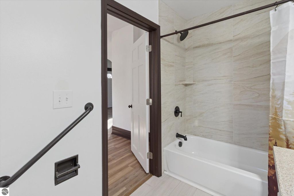 Modern bathroom featuring a white bathtub, tiled walls, and new fixtures, showcasing recent renovations in a home for sale at 117 E Wright Avenue, Shepherd, MI.
