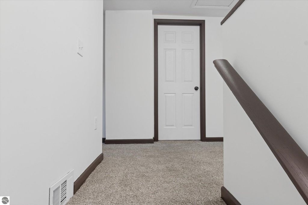 Hallway view in renovated home at 117 E Wright Avenue, featuring white walls, carpeted flooring, and a closed door leading to a room, emphasizing modern updates and spacious layout.