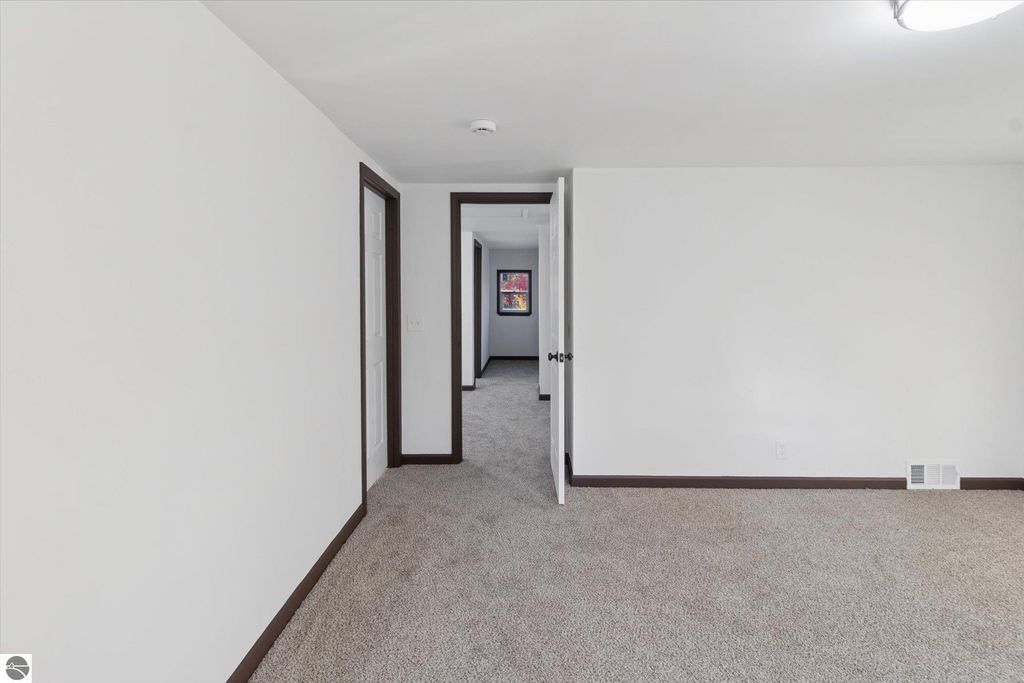 Renovated interior hallway of a 3-bedroom home in Shepherd, MI, featuring new carpet, white walls, and doorways leading to additional rooms.