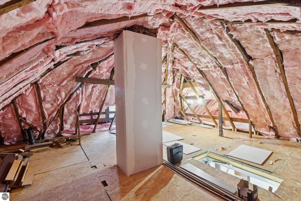 Attic space with pink insulation and unfinished drywall, showcasing renovation progress in a 3-bedroom home at 117 E Wright Avenue, Shepherd, MI.