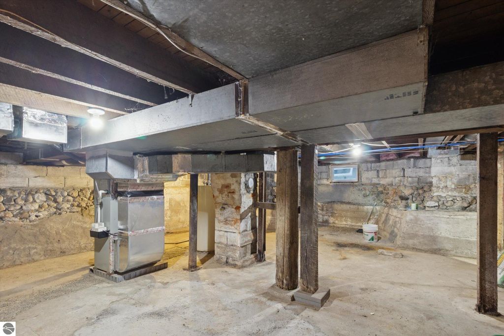 Basement interior of a renovated home at 117 E Wright Avenue, featuring exposed wooden beams, metal ductwork, and a furnace, showcasing recent updates and structural integrity.
