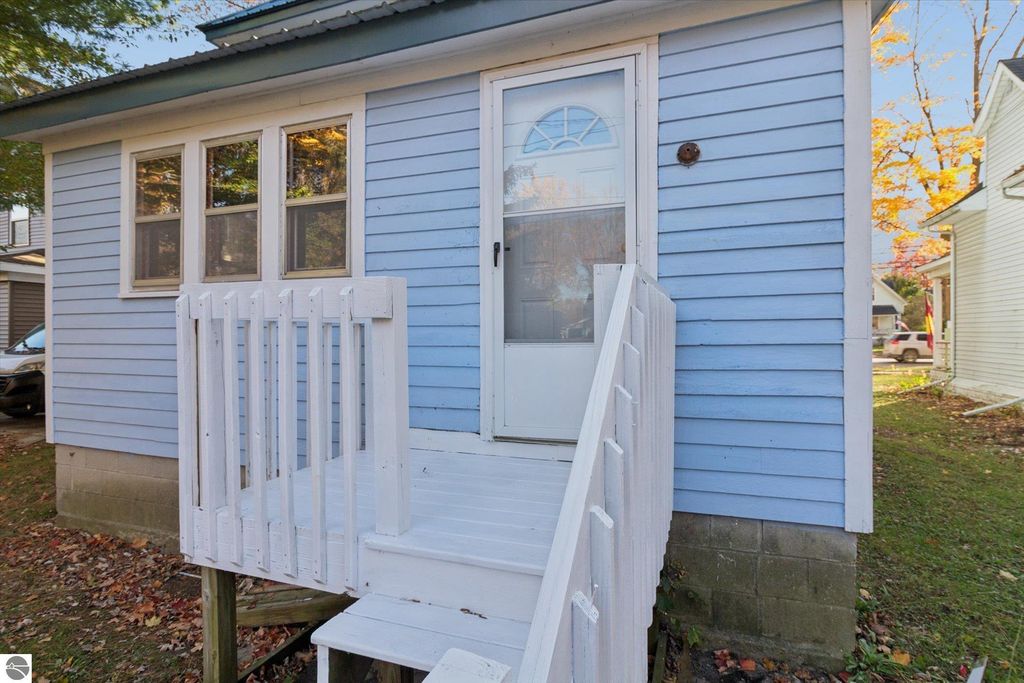 Exterior view of renovated blue home at 117 E Wright Avenue, featuring white steps and railing, large windows, and a welcoming front door, set in a picturesque downtown Shepherd neighborhood.