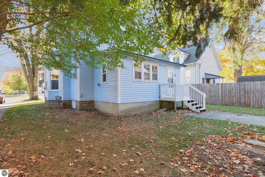 Renovated blue home exterior with white porch steps, surrounded by autumn leaves, located at 117 E Wright Avenue, Shepherd, MI.