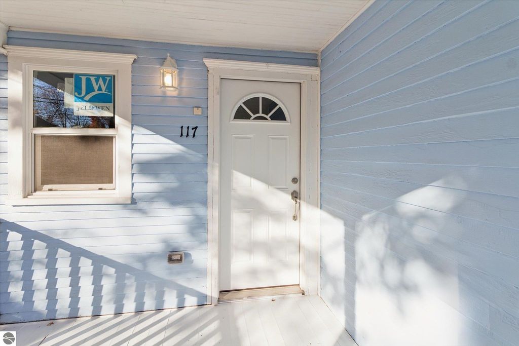 Front entrance of renovated home at 117 E Wright Avenue, featuring a white door, blue siding, and Jeld-Wen window logo, highlighting the property's modern updates.