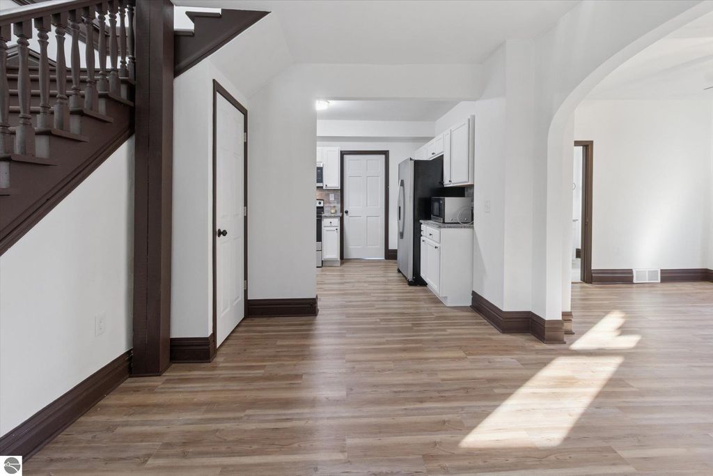 Renovated interior view of 3-bedroom home at 117 E Wright Avenue, featuring open layout, modern kitchen with stainless steel appliances, new flooring, and staircase.