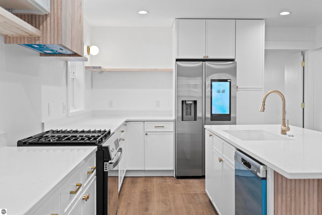 Modern kitchen featuring stainless steel appliances, quartz countertops, custom cabinetry, and open shelving, showcasing a bright and efficient design ideal for contemporary living in Traverse City.