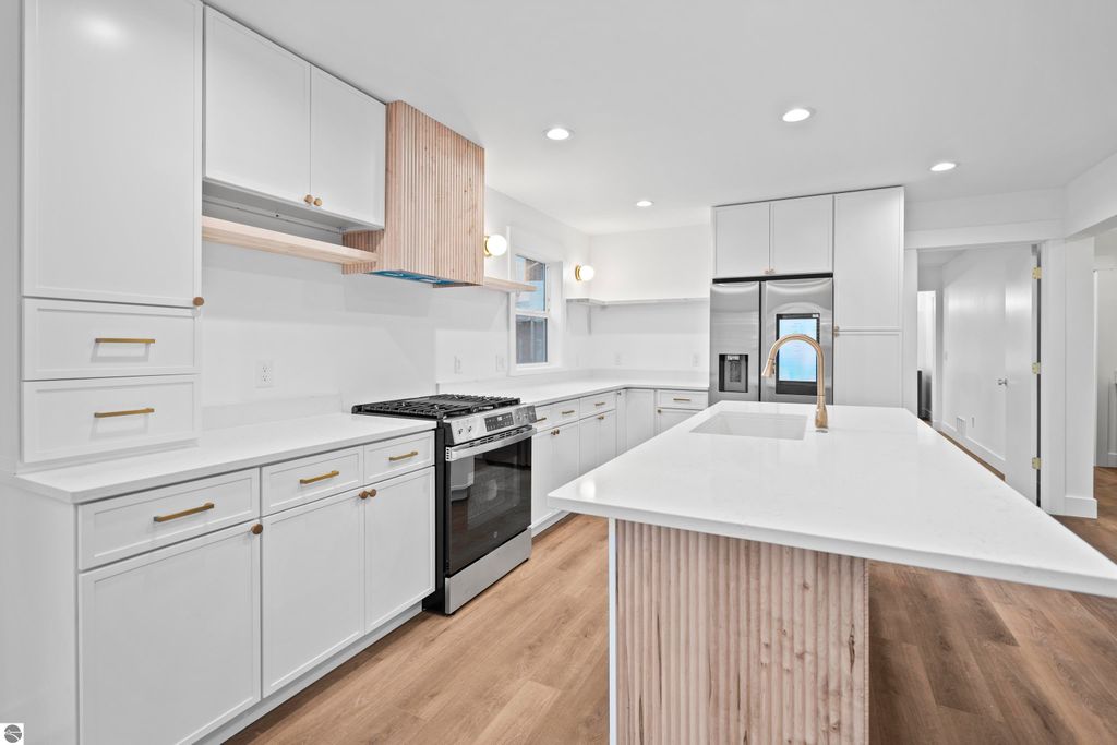Modern kitchen with quartz countertops, custom cabinetry, stainless steel appliances, and a handcrafted vent hood in a new home at 2737 Ruby Street, Traverse City, MI.