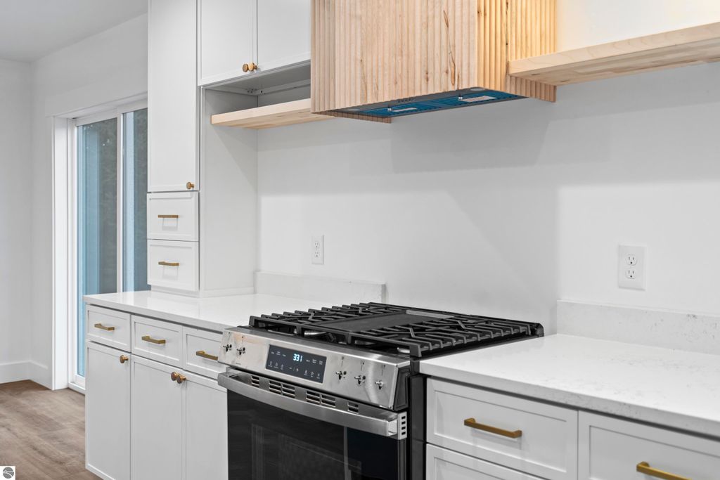 Modern kitchen featuring custom cabinetry, quartz countertops, handcrafted vent hood, and energy-efficient stainless steel appliances in a newly built home at 2737 Ruby Street, Traverse City, MI.