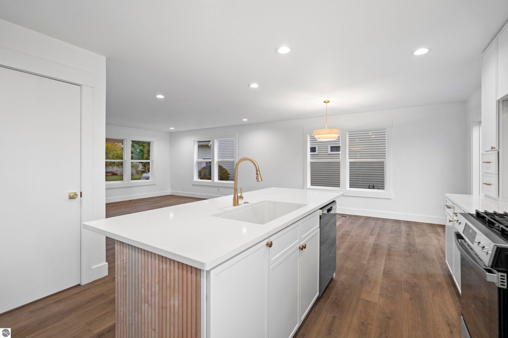 Modern kitchen interior featuring quartz countertops, stainless steel appliances, and open shelving, showcasing craftsmanship in a new home at 2737 Ruby Street, Traverse City, MI.