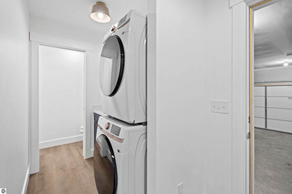 Main-floor laundry area featuring stacked washer and dryer, modern design, and access to garage, highlighting convenience in new Traverse City home.