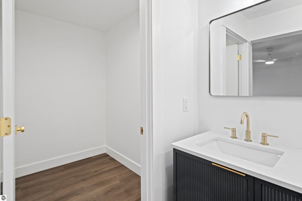 Modern bathroom with sleek black cabinetry, gold fixtures, and a large mirror, showcasing a bright, minimalist design in a new home at 2737 Ruby Street, Traverse City, MI.