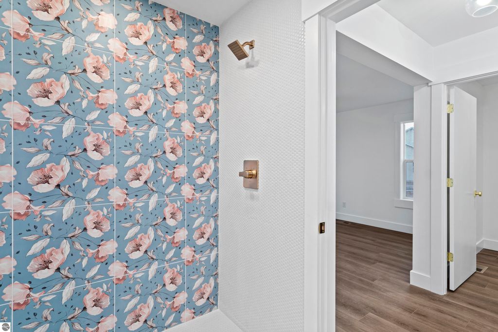 Floral accent wall with pink and white flowers on blue tile, showcasing modern bathroom design elements and craftsmanship in new home at 2737 Ruby Street, Traverse City, MI.