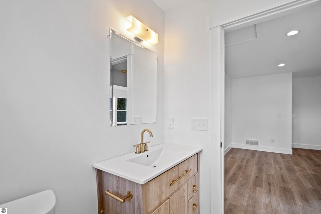 Modern bathroom vanity with quartz countertop, gold faucet, and mirror in newly built home at 2737 Ruby Street, Traverse City, showcasing quality finishes and craftsmanship.