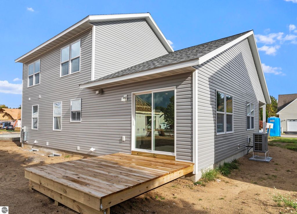 Newly constructed home exterior in Emerald Hills community, featuring modern siding, a wooden deck, and large windows, showcasing craftsmanship and design relevant to the Traverse City real estate listing.