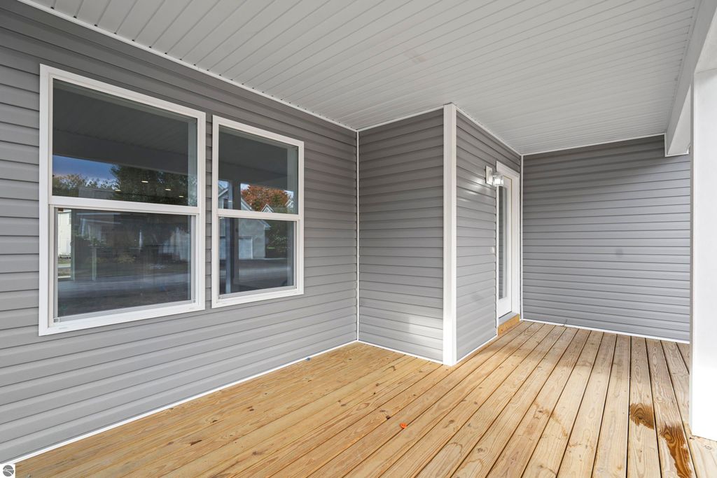 Newly constructed porch area with gray siding, large windows, and wooden flooring, showcasing modern design elements of the home at 2737 Ruby Street, Traverse City, MI.