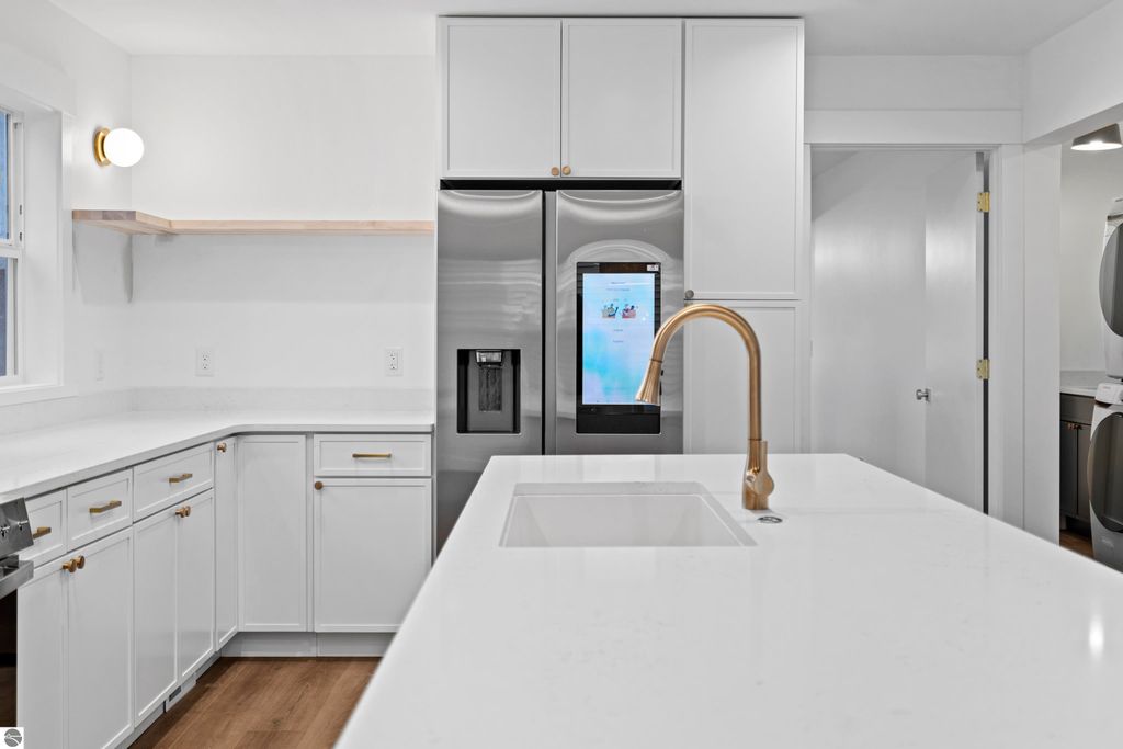Modern kitchen featuring white cabinetry, quartz countertops, energy-efficient stainless steel appliances, and a gold faucet, showcasing a bright and open design ideal for the property at 2737 Ruby Street, Traverse City, MI.
