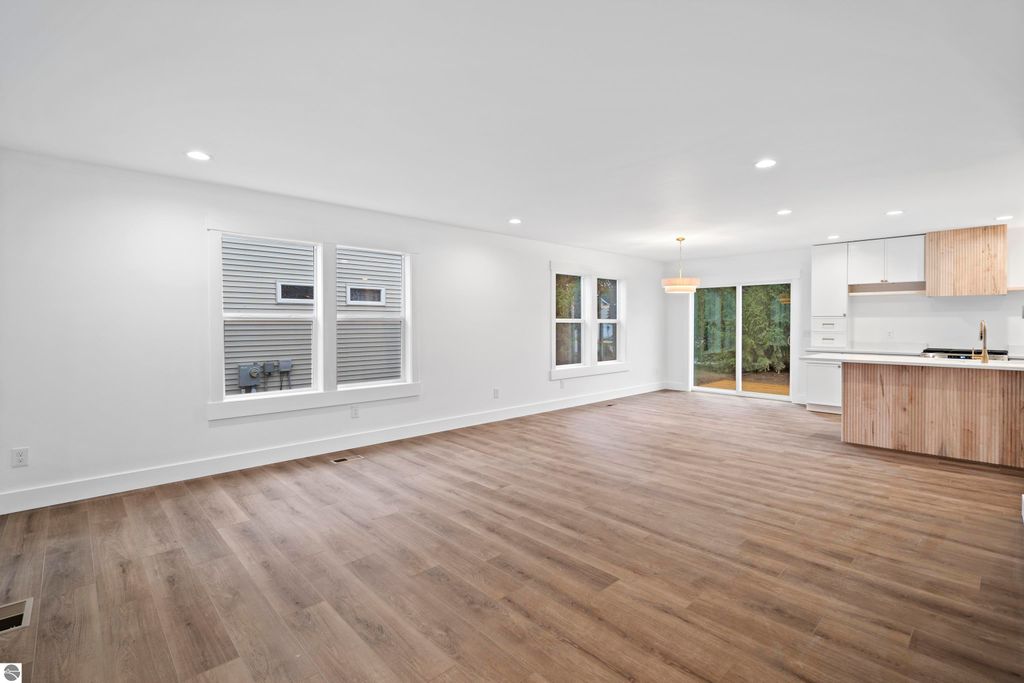 Open-concept living space featuring modern kitchen with wood accents, large windows, and natural light in Traverse City home at 2737 Ruby Street.