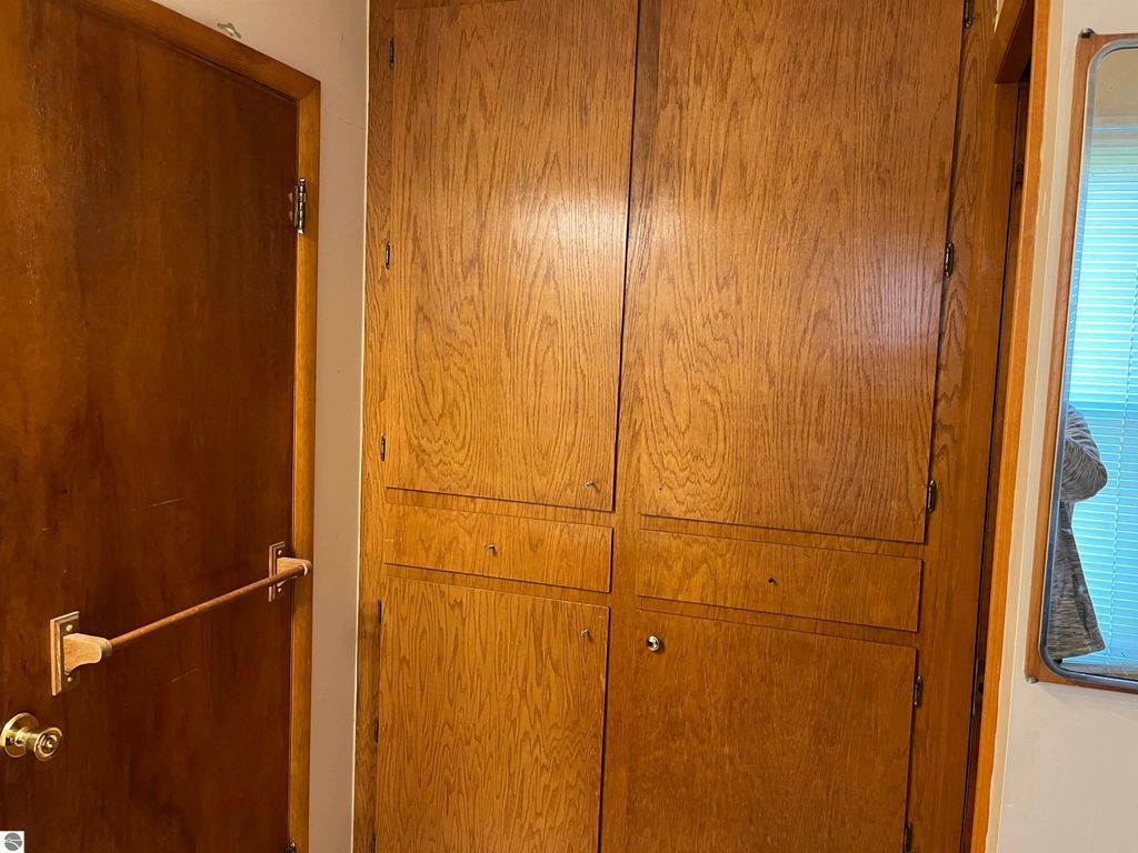 Wooden storage cabinets and door in farmhouse entryway, showcasing rustic design elements and functionality in a four-bedroom home at 6034 W Sterling Road, Sterling, MI.