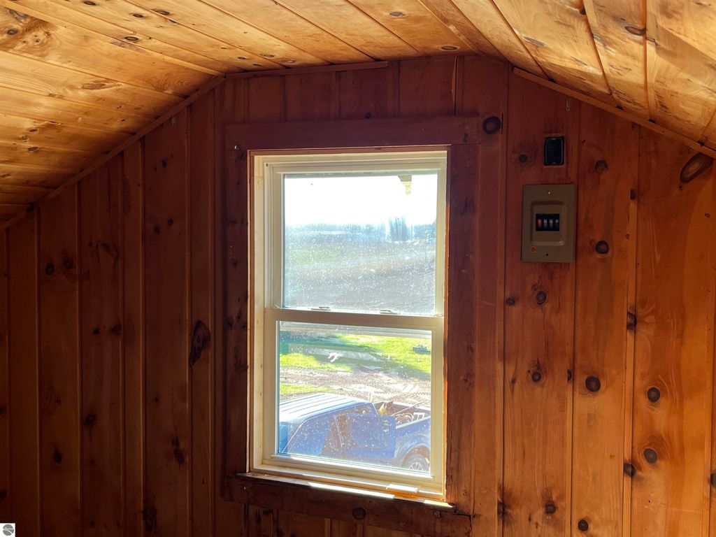 Wood-paneled interior of a farmhouse with a window showing rural views, featuring a blue vehicle outside, emphasizing the property's serene setting on 2.5 acres.