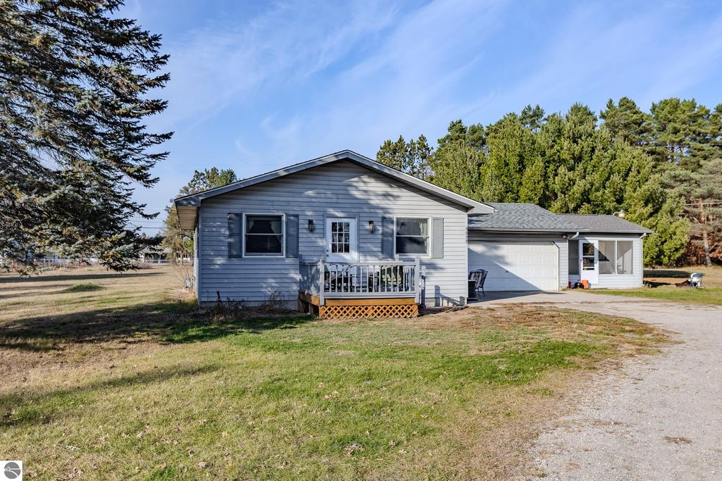 Single-family home at 2265 Michigan Avenue, Prescott, MI, featuring a front porch, attached 2-car garage, and surrounded by trees on a spacious 3-acre lot.