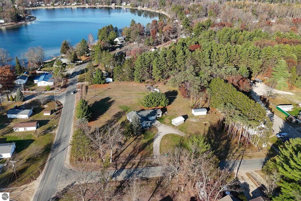 Aerial view of a residential area near Skidway Lake, showcasing a 3-acre property with a house, multiple garages, and surrounding trees, highlighting the peaceful setting ideal for outdoor activities.