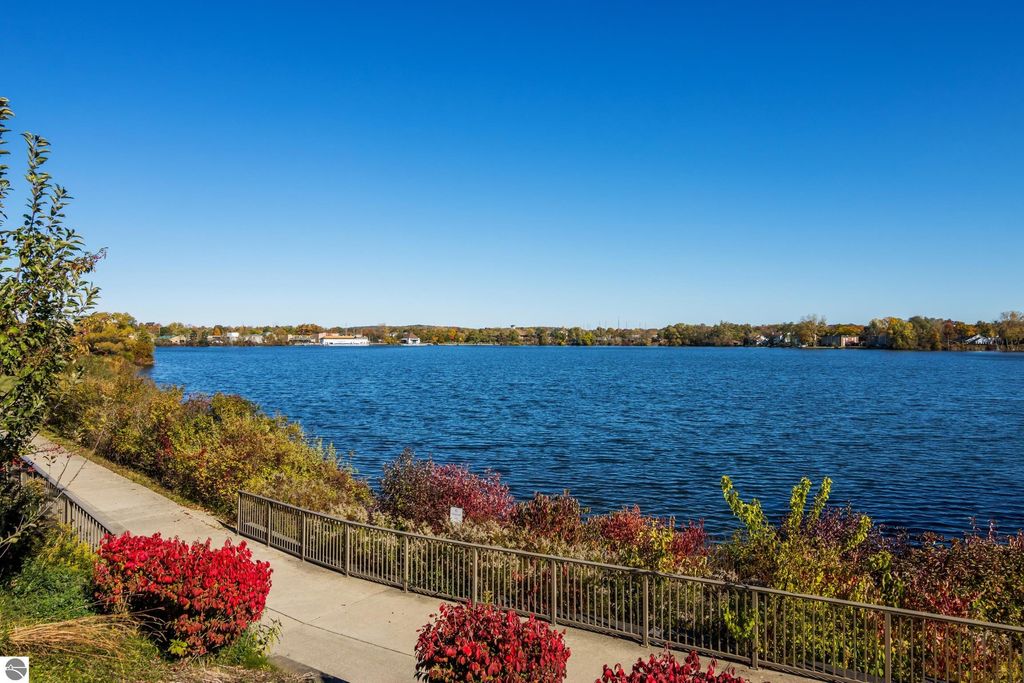 Lakeside view of Boardman Lake with colorful foliage and walking path, showcasing the serene environment near 1122 Lake Ridge Drive condo in Traverse City, MI.