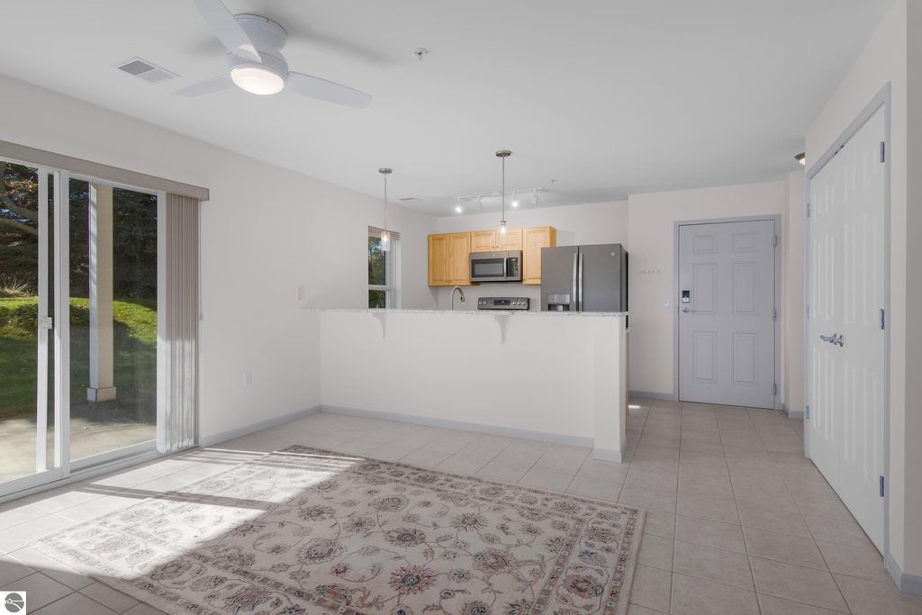 Updated kitchen and living area of a 2BR/2BA condo in Traverse City, featuring south-facing patio access, modern appliances, and stylish decor, ideal for lakeside living.