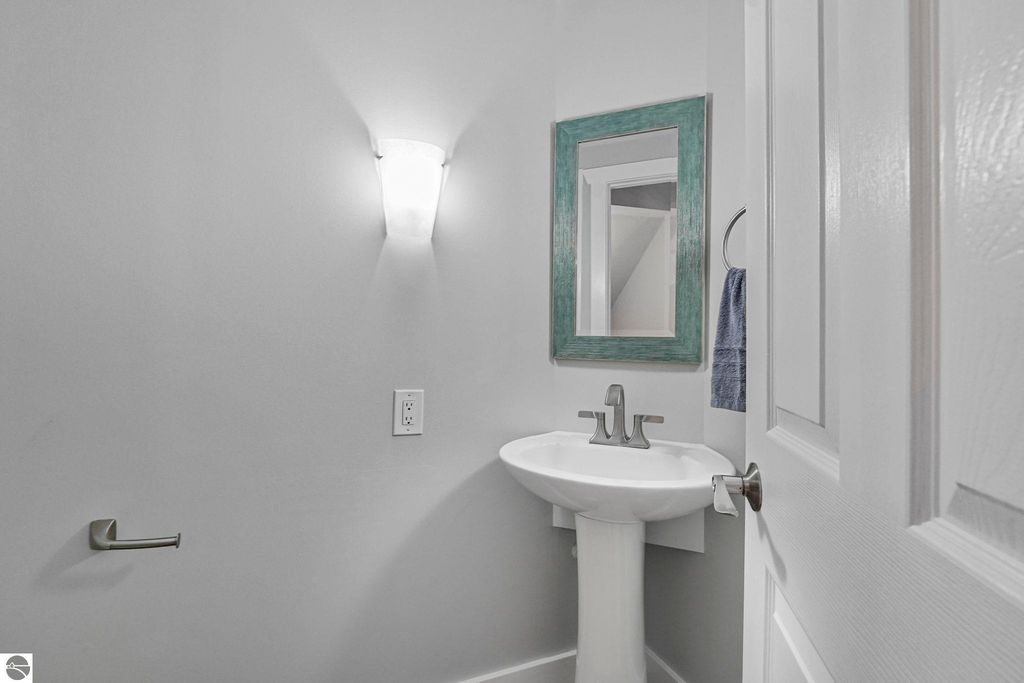 Powder room with pedestal sink, decorative mirror, and modern lighting, showcasing the townhouse's updated interior design.