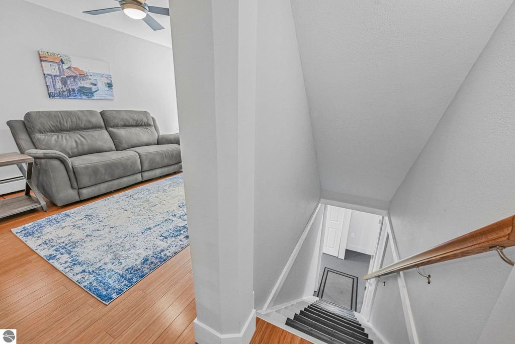 Bright living room with gray couch and decorative rug, staircase leading to upper level, showcasing modern townhouse design in Traverse City, MI.