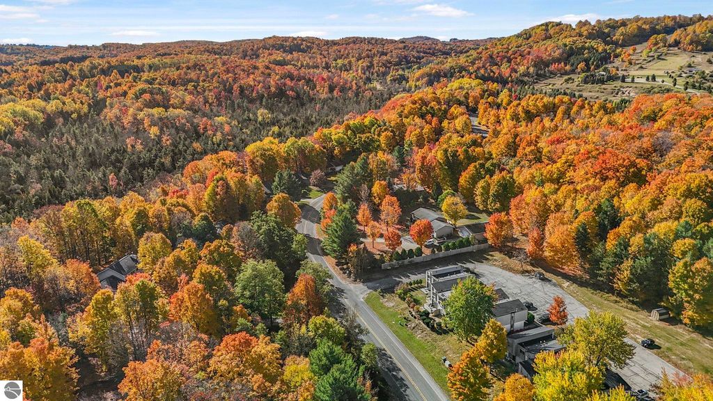 Aerial view of vibrant autumn foliage surrounding residential areas near Traverse City, Michigan, showcasing colorful trees and scenic landscape.