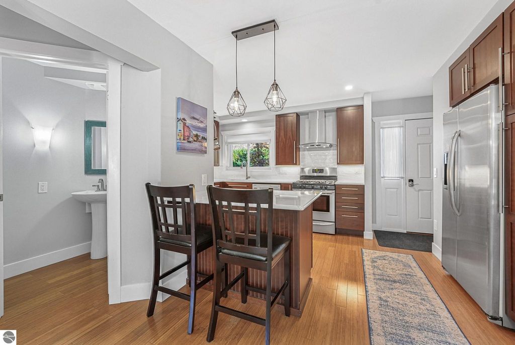 Modern kitchen interior featuring an island with seating, stainless steel appliances, and hardwood flooring in a Traverse City townhouse.