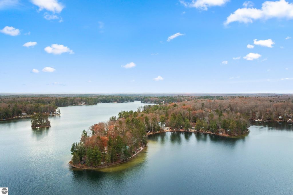 Aerial view of Spider Lake, showcasing lush greenery and serene waterfront, ideal for relaxed Up North living near Traverse City, MI.