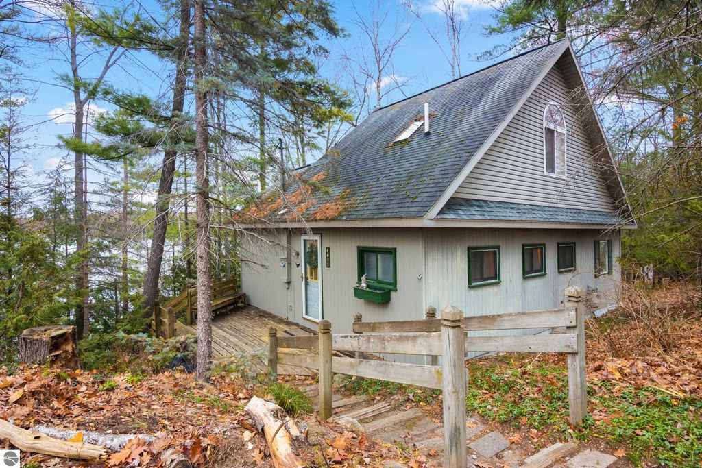 Waterfront home at 4411 Lakeview Trail, Traverse City, MI, featuring a sloped entryway, surrounded by trees, with a view of Spider Lake in the background.