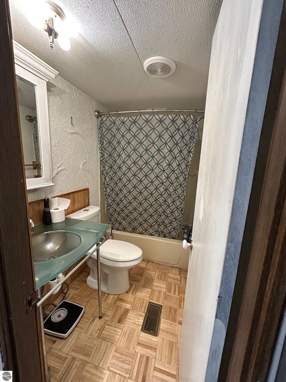 Updated bathroom with glass sink, patterned shower curtain, and modern fixtures in a cozy residential setting.