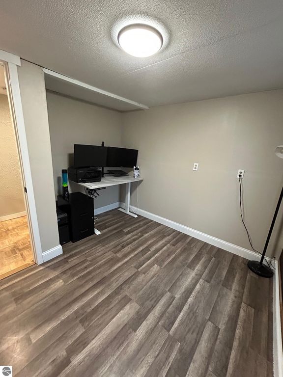 Updated interior office space with dual monitors, laminate flooring, and modern lighting, showcasing a functional workspace in a residential property for sale at 3780 E North County Line Road, St Louis, MI.