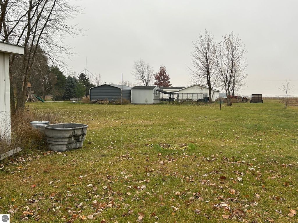 Spacious yard at 3780 E North County Line Road, featuring outbuildings, trees, and play structure, showcasing country living on 1.87 acres.
