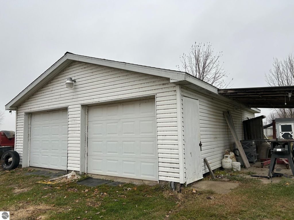 Two-car heated garage with white siding, concrete foundation, and adjacent storage areas on a residential property in St. Louis, MI.