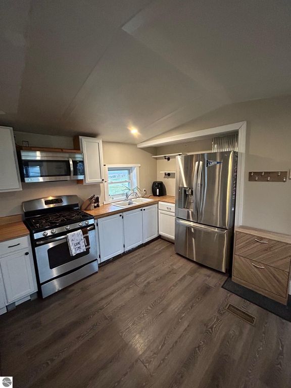 Updated kitchen featuring stainless steel appliances, including a gas stove and refrigerator, modern cabinetry, and wooden countertops, highlighting a cozy and functional cooking space in a home for sale at 3780 E North County Line Road, St Louis, MI.
