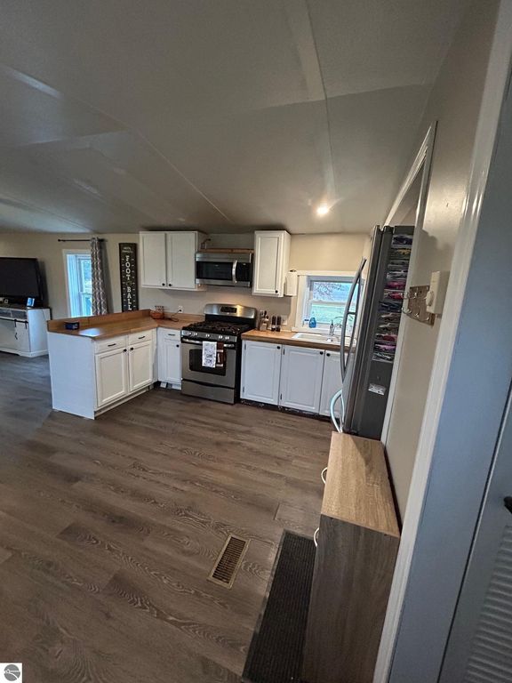Updated kitchen with white cabinetry, stainless steel appliances, and laminate flooring, showcasing a cozy and modern space in a residential property for sale in St Louis, MI.