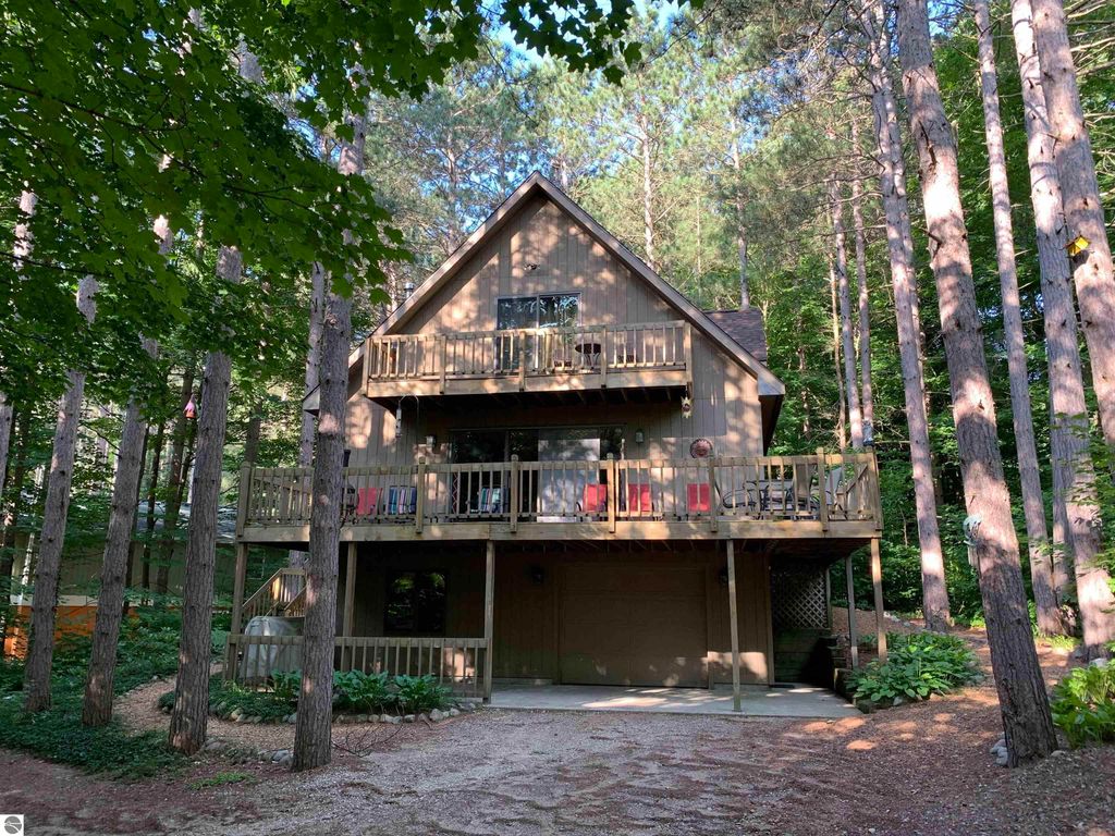 Quaint Crystal Mountain cottage nestled among tall pines, featuring spacious deck, multiple balconies, and garage, located near ski slopes and amenities in Thompsonville, MI.