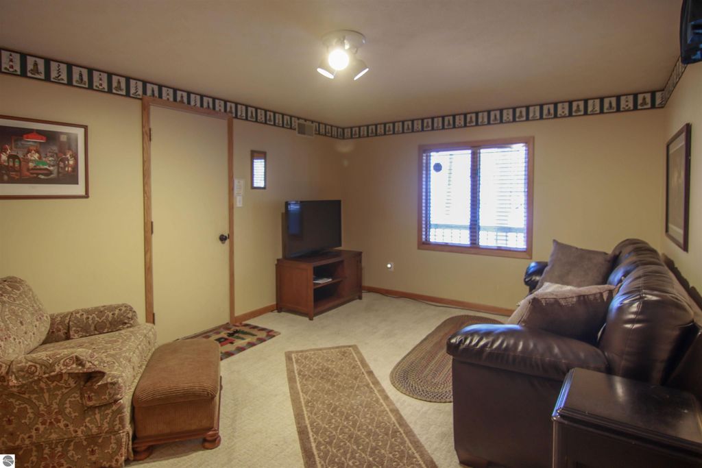 Cozy living room in Crystal Mountain cottage featuring a patterned rug, plush seating, a television, and decorative wall art, emphasizing a welcoming space for relaxation near ski slopes in Thompsonville, MI.