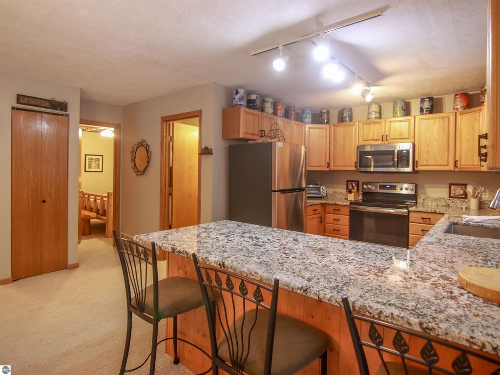 Modern kitchen interior with granite countertops, stainless steel appliances, and wooden cabinetry in a cozy Crystal Mountain cottage setting.