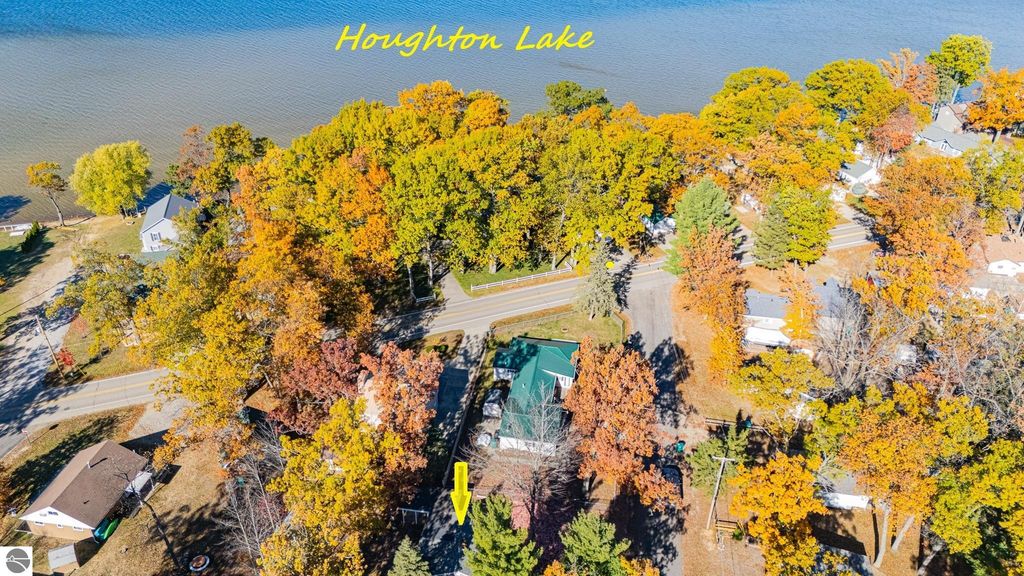 Aerial view of Houghton Lake with vibrant fall foliage, showcasing nearby cottages and roads, emphasizing the scenic location of the property at 133 Maple Bluffs Avenue, Prudenville, MI.