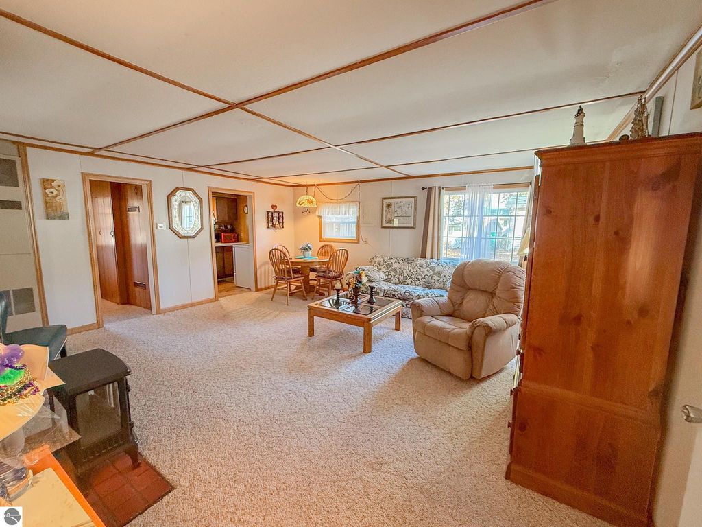 Cozy living room interior of a two-bedroom cottage at 133 Maple Bluffs Avenue, featuring a gas fireplace, dining area, and natural light from windows, ideal for up-north getaway living.
