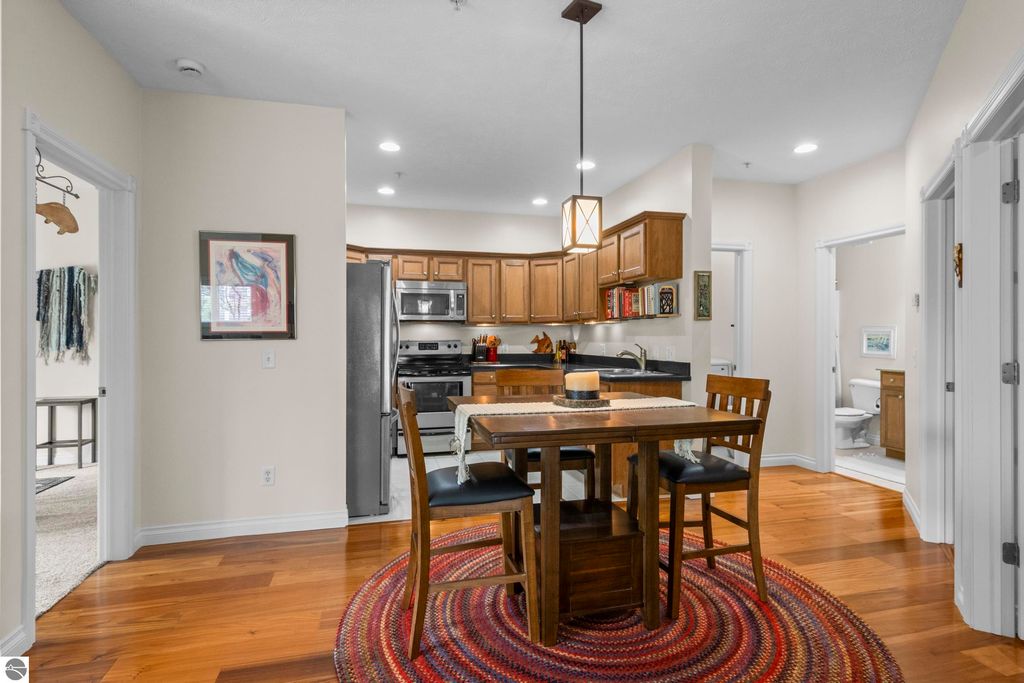 Modern kitchen and dining area in a 2-bedroom condo, featuring wood floors, stainless steel appliances, and a cozy dining table with chairs, set in a bright, open layout.